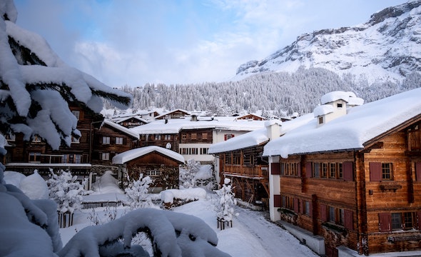 a snowy mountain village with wooden houses and tall snow-covered trees