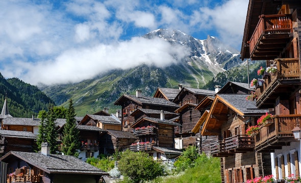 A village in the Alps, surrounded by majestic mountains under a cloudy sky